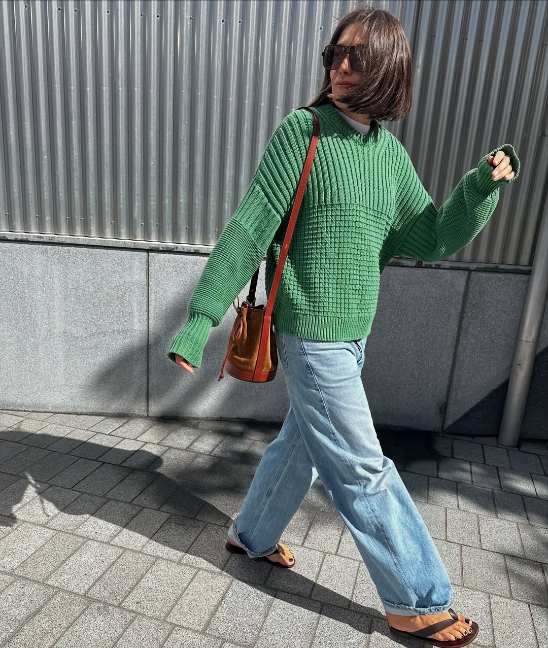 Mulher usando roupa jeans de algema com suéter verde e chinelos