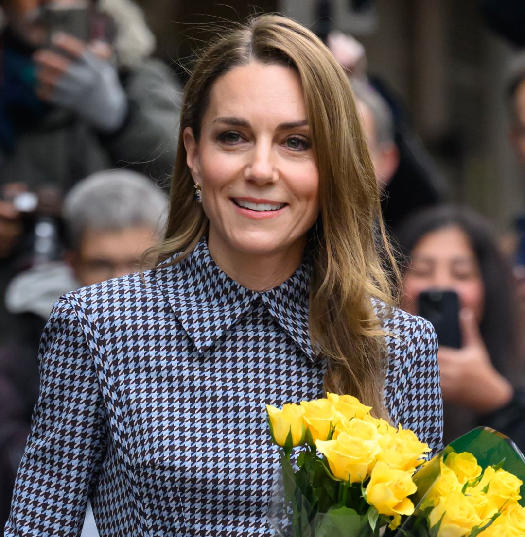 Kate Middleton wearing a checkered dress holding yellow flowers