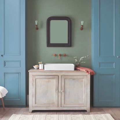 A bathroom with the wall painted in Dulux Heritage Sage Green and the storage cupboards painted in Boathouse Blue