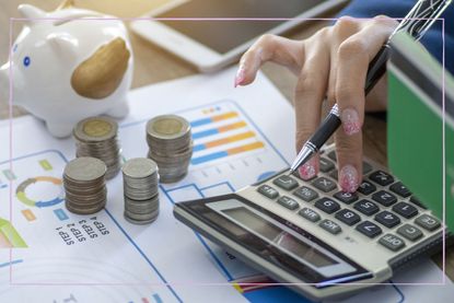 A person using a calculator next to a pile of coins and payslips