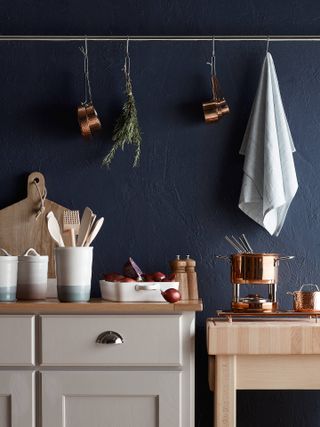 Copper pots and pans in a dark blue kitchen