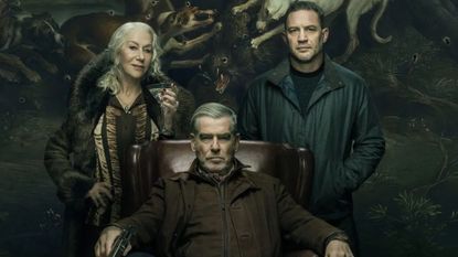 Conrad sits in a chair while Maeve and Harry stand either side of it