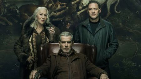 Conrad sits in a chair while Maeve and Harry stand either side of it