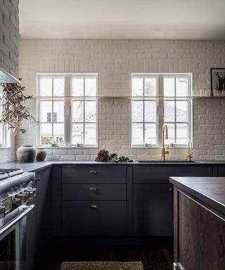 Black kitchen with white brick walls and windows