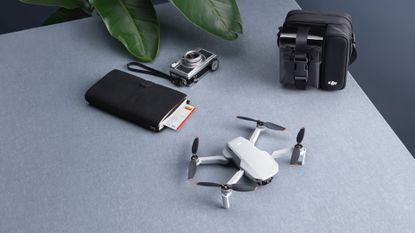 DJI Mini 2 drone on a tabletop, next to a diary, camera and bag