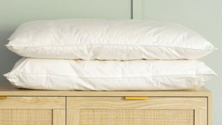 Two white pillows on top of a wooden cabinet.