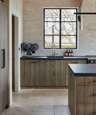 Reclaimed wood kitchen cabinets with black worktop and large Crittall style window