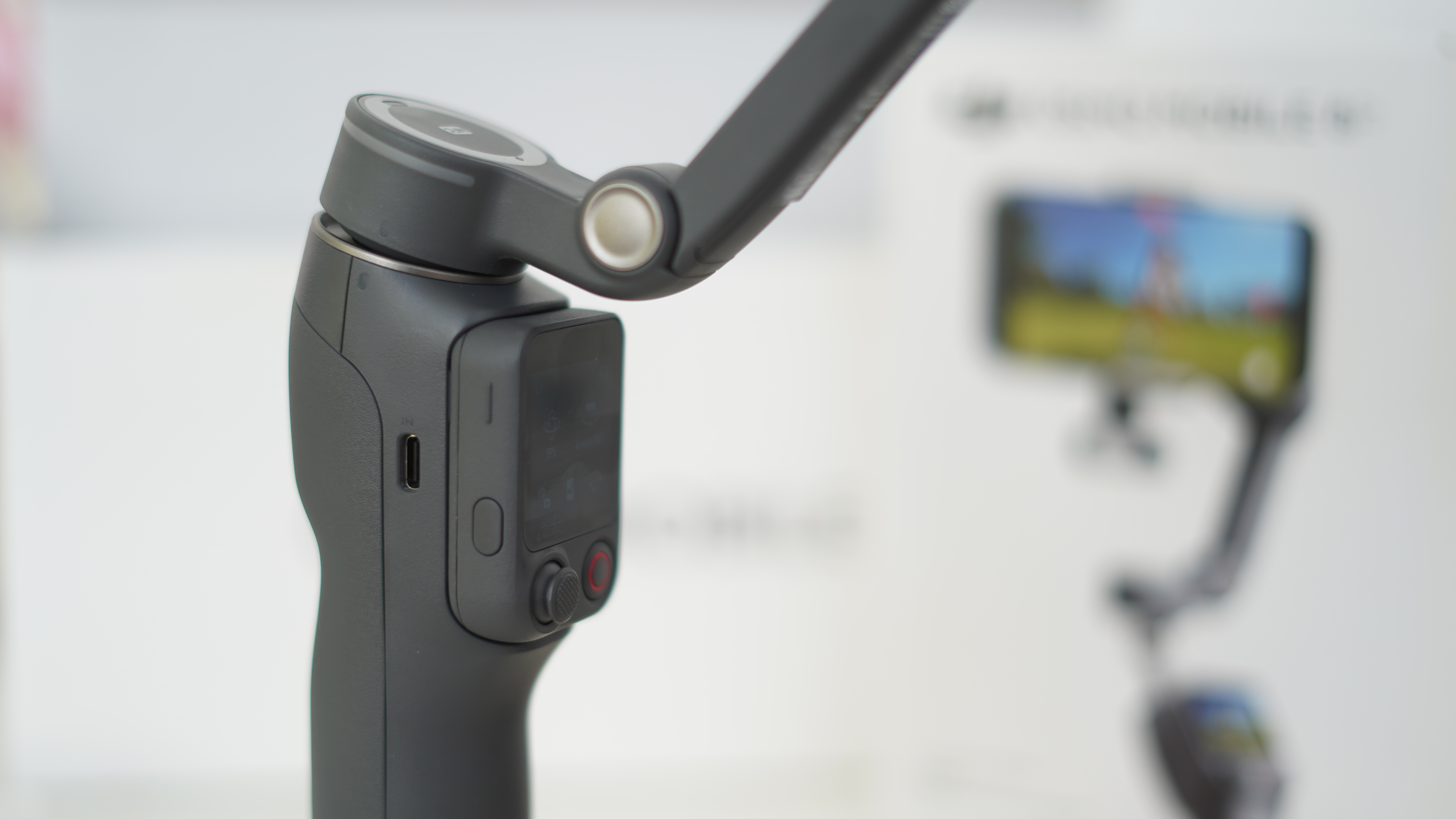 DJI Osmo Mobile 8P handle with box behind and remote in holder