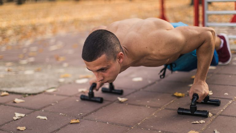 Man using push up handles, part of a home gym setup