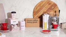 A modern marble kitchen countertop with selection of Grind coffee products including pods and pink single-use coffee cup