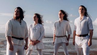 Wytch Hazel dressed in white, backs against the sea