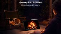 A person sitting outside in the woods at night watching a campfire on a Samsung tablet sitting on a table