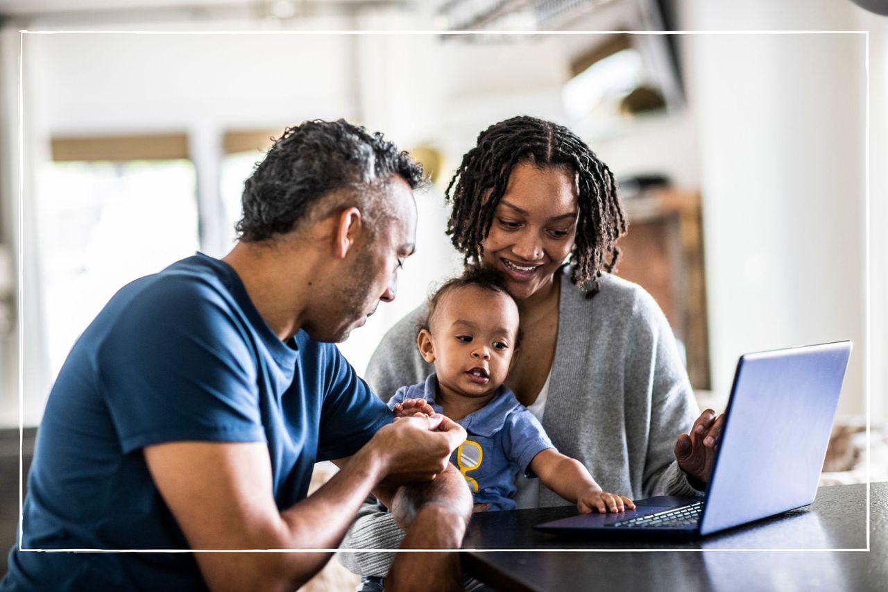 Parents holding young baby while looking at laptop