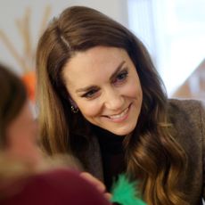 Princess Kate smiling and sitting at a table with families
