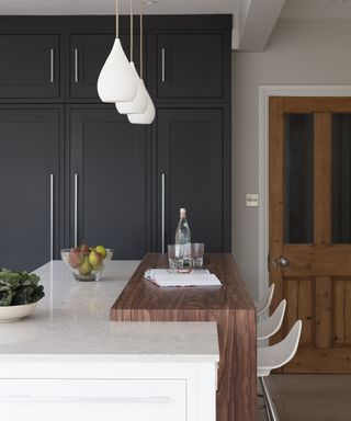 Breakfast bar ideas shown in dark wood, set above a white marble kitchen island with dark gray cabinetry.