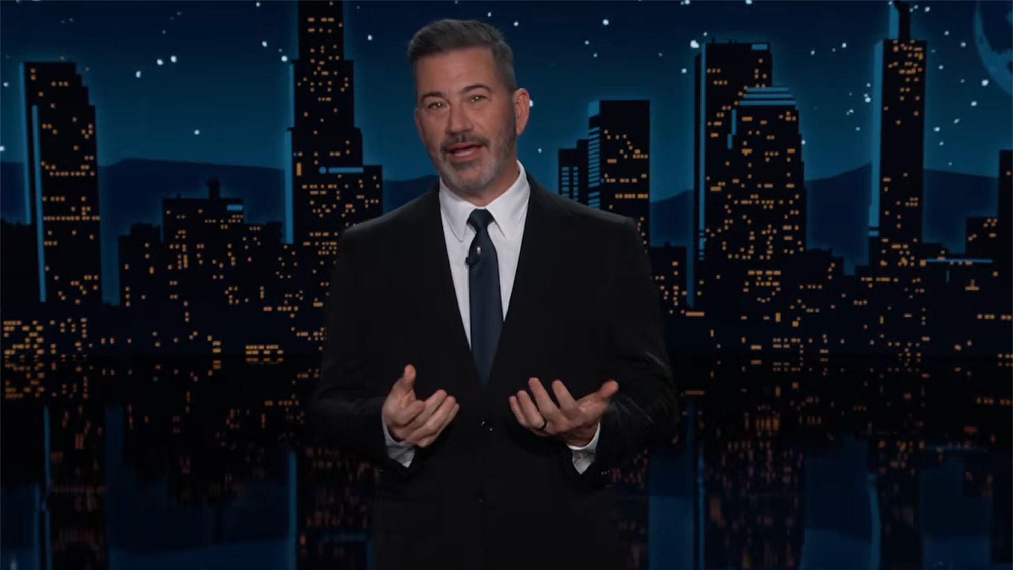 Jimmy Kimmel holds up his hands while joking about the White House during the October 15th episode of Jimmy Kimmel Live. He has on a suit and tie.