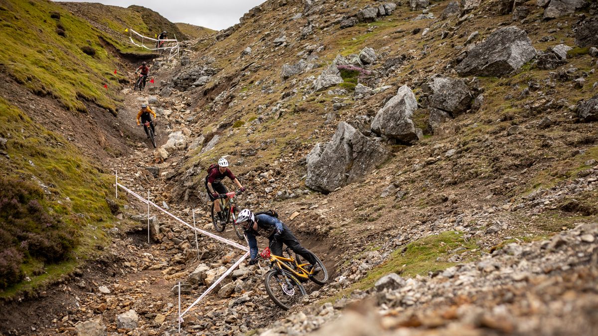 A group of mountain bikers ride down a rocky gully