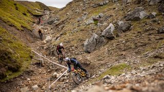 A group of mountain bikers ride down a rocky gully