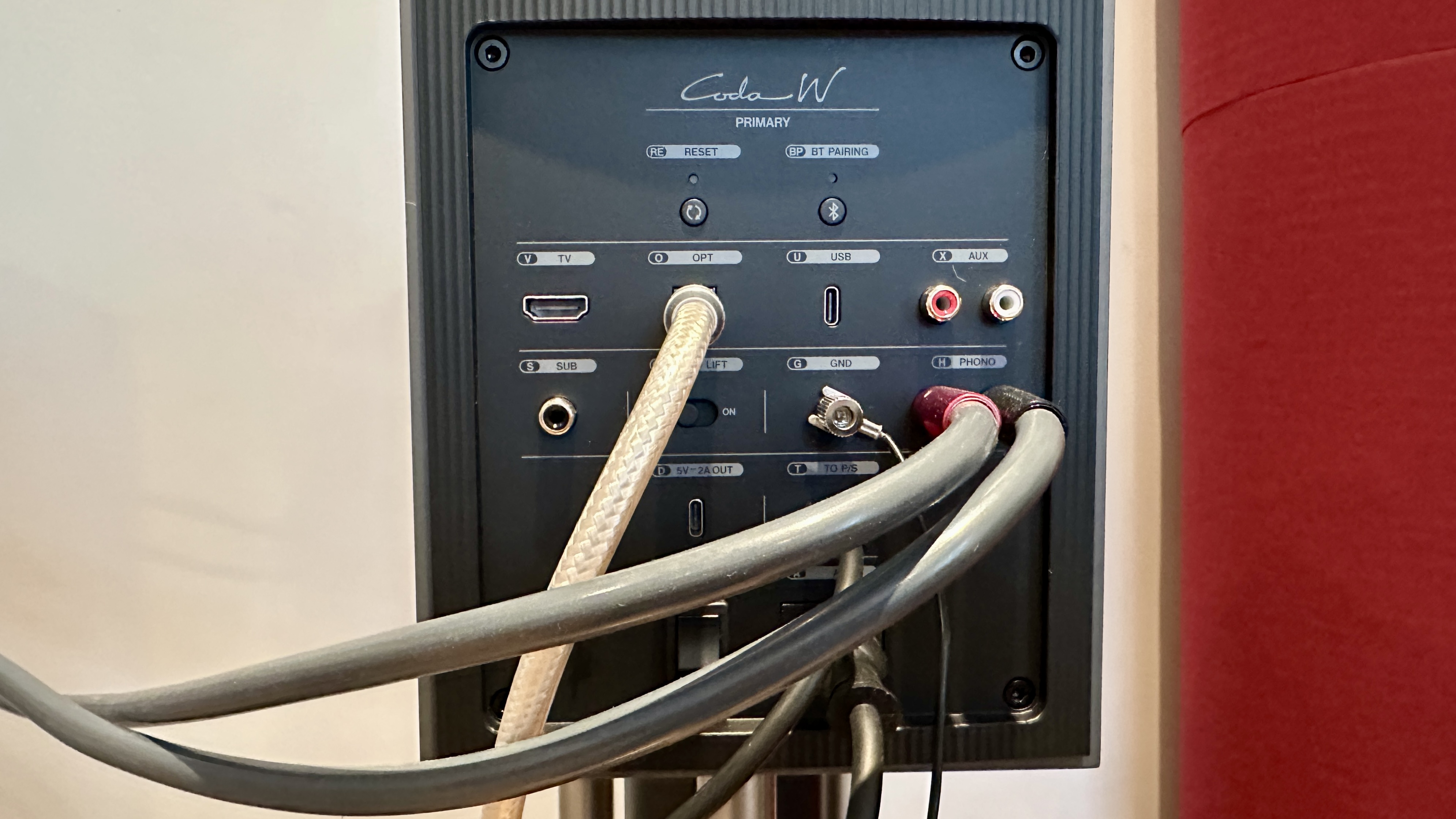 Rear panel of the KEF Coda W active speakers, with wired connections and cables visible.