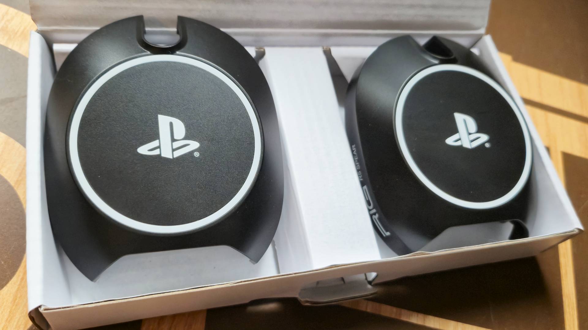 Photo of the RIG mod plates - two plastic coverings that have white PlayStation logos on them.