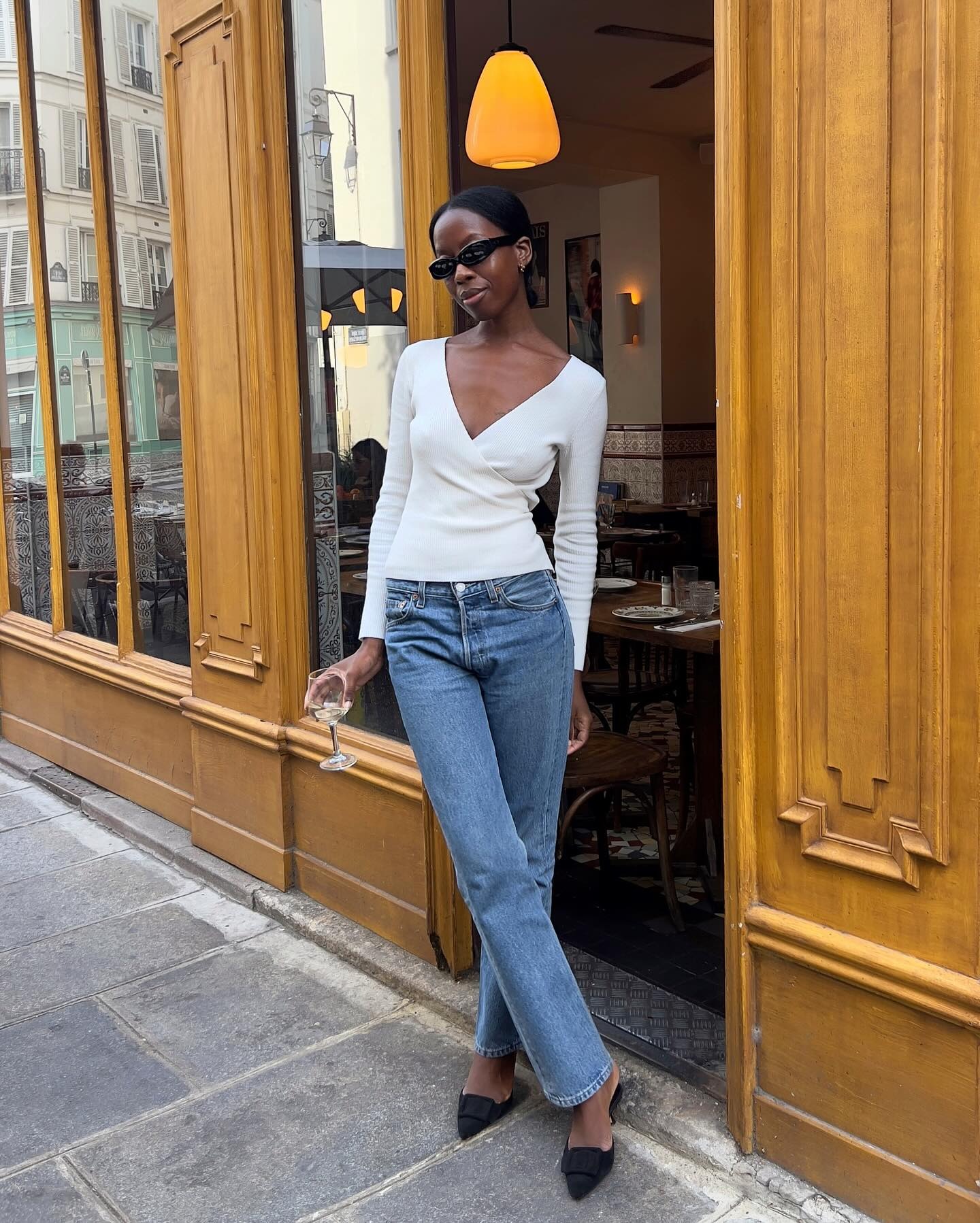 French influencer @sylviemus_ stands outside of a restaurant in Paris wearing black closed-toe heeled mules.