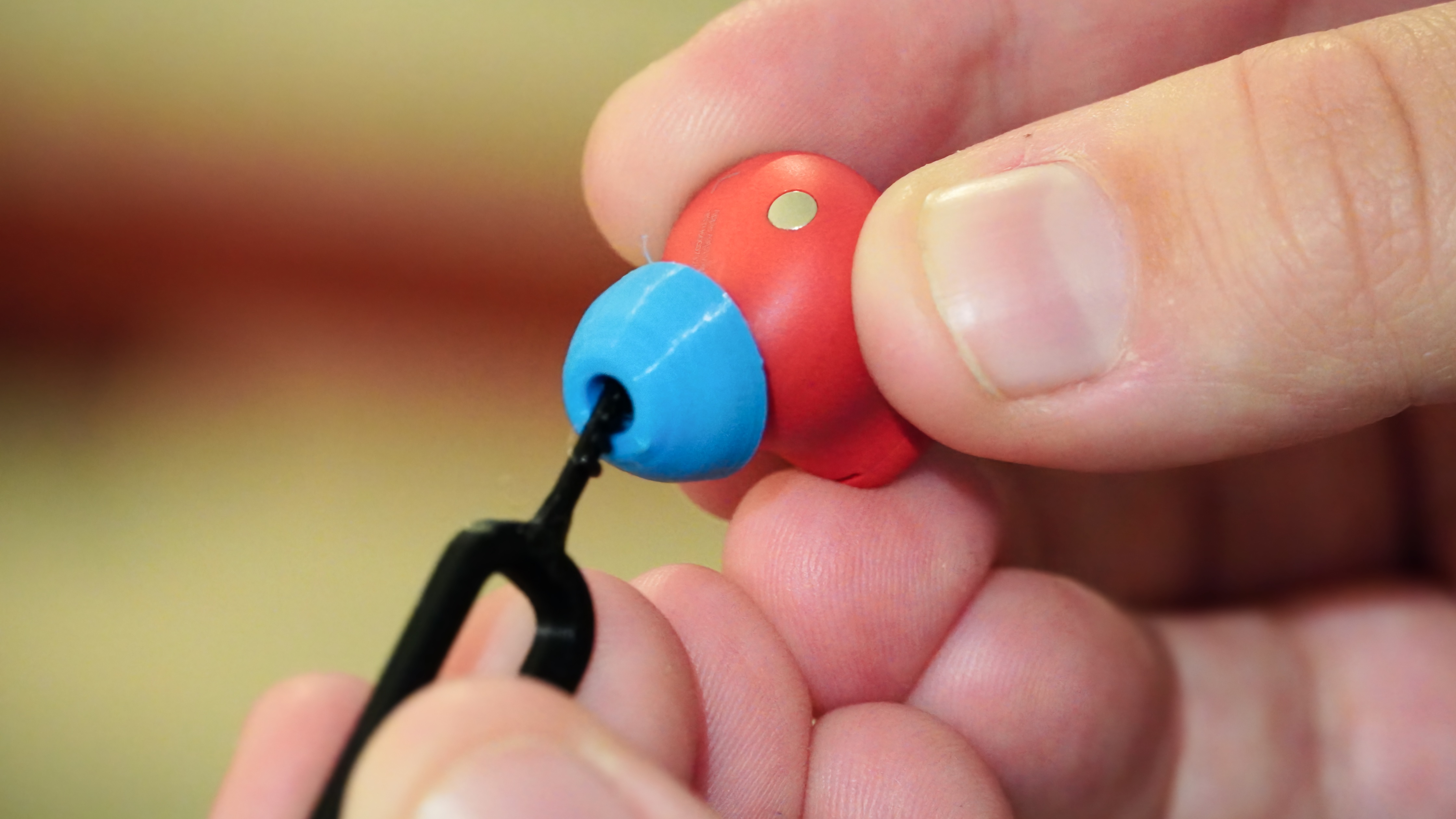 The 3D-printed earbud cleaning tool in use on a pair of earbuds.