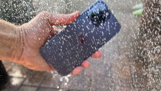 En Apple iPhone 14 Pro Max holdes i en dusjstråle