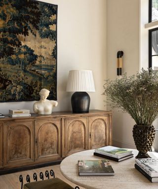 light bright neutral entryway with light walls and floor with a large rustic credenza sitting beneath a large antique tapestry