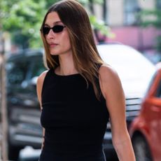Hailey Bieber walking in Manhattan wearing a black tank top and carrying a baby bag