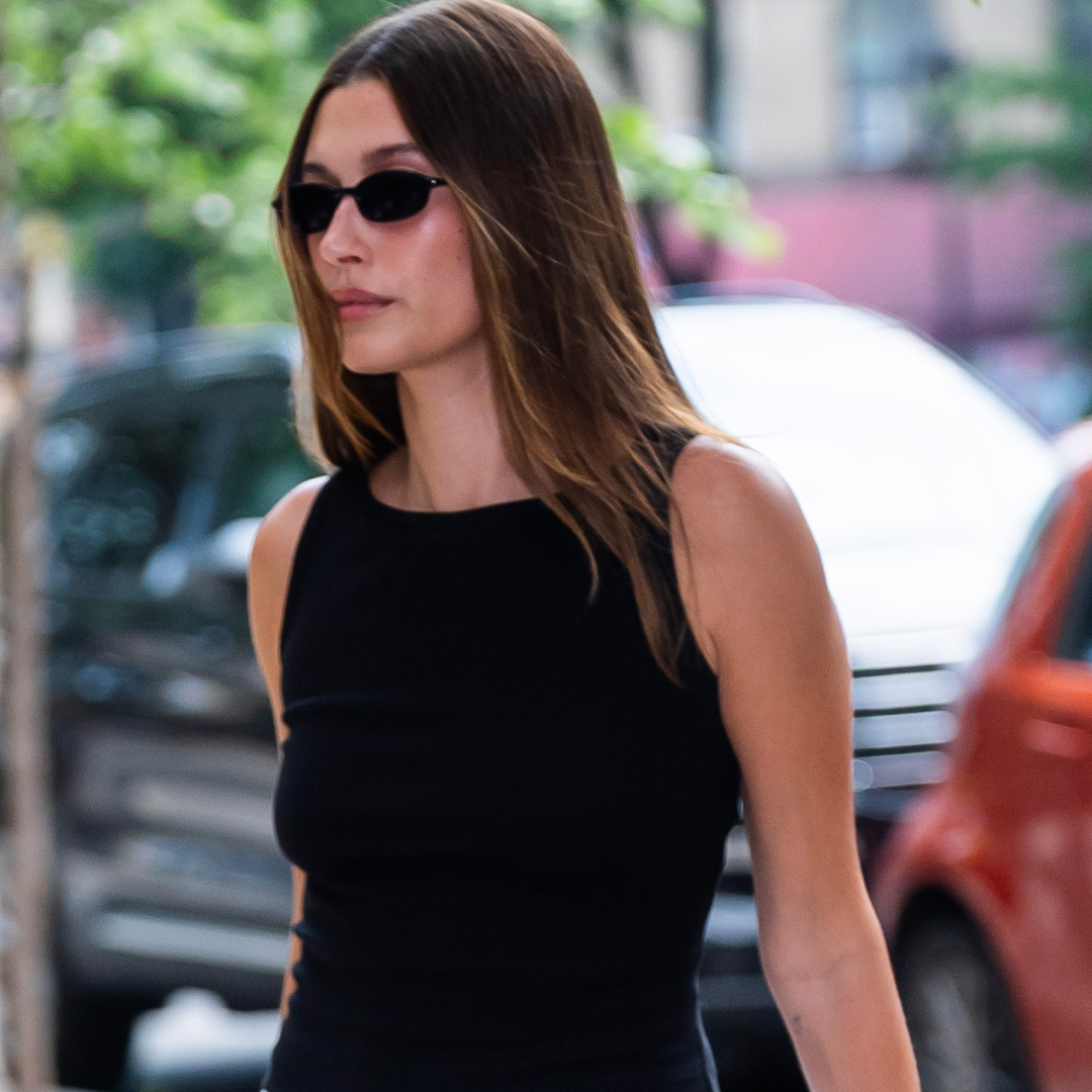 Hailey Bieber walking in Manhattan wearing a black tank top and carrying a baby bag