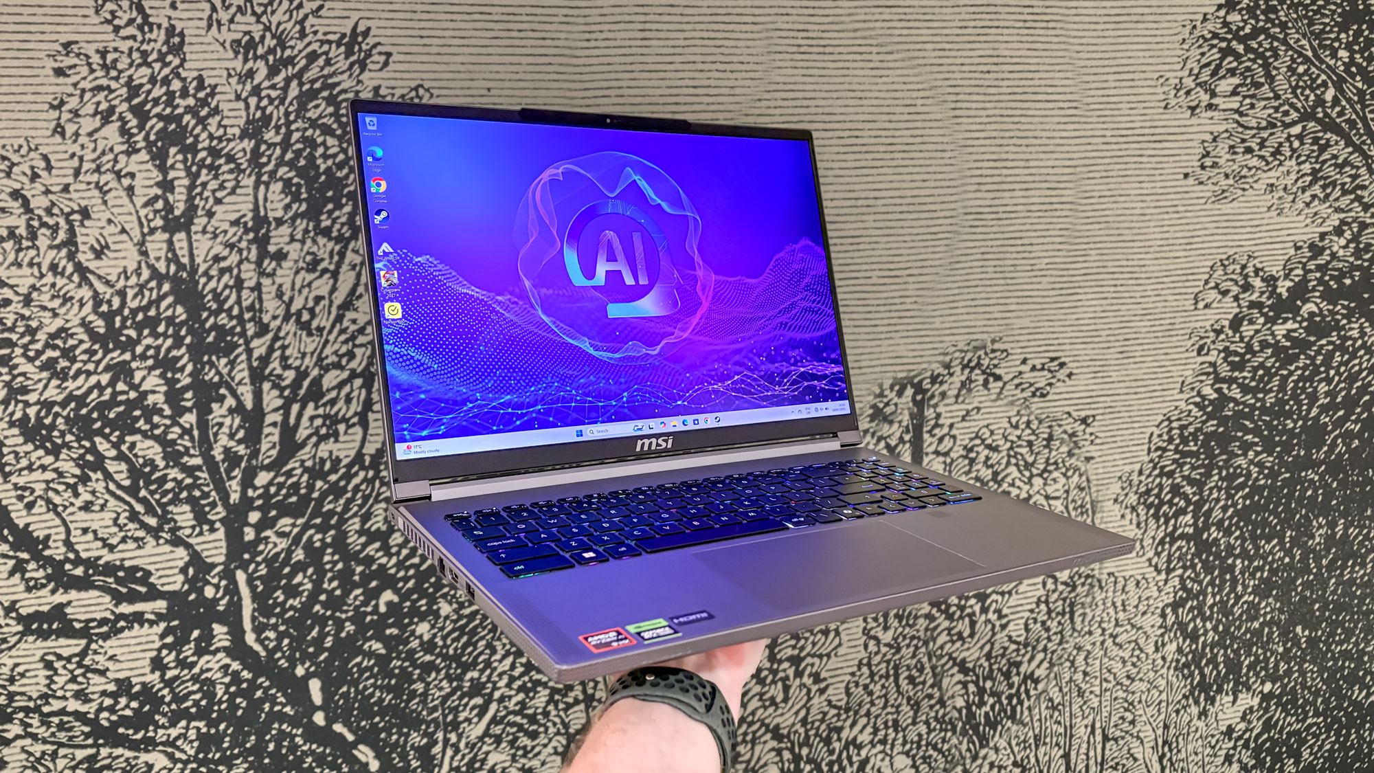 MSI Creator A16 AI+ held in hand with tree wallpaper drawing in the background