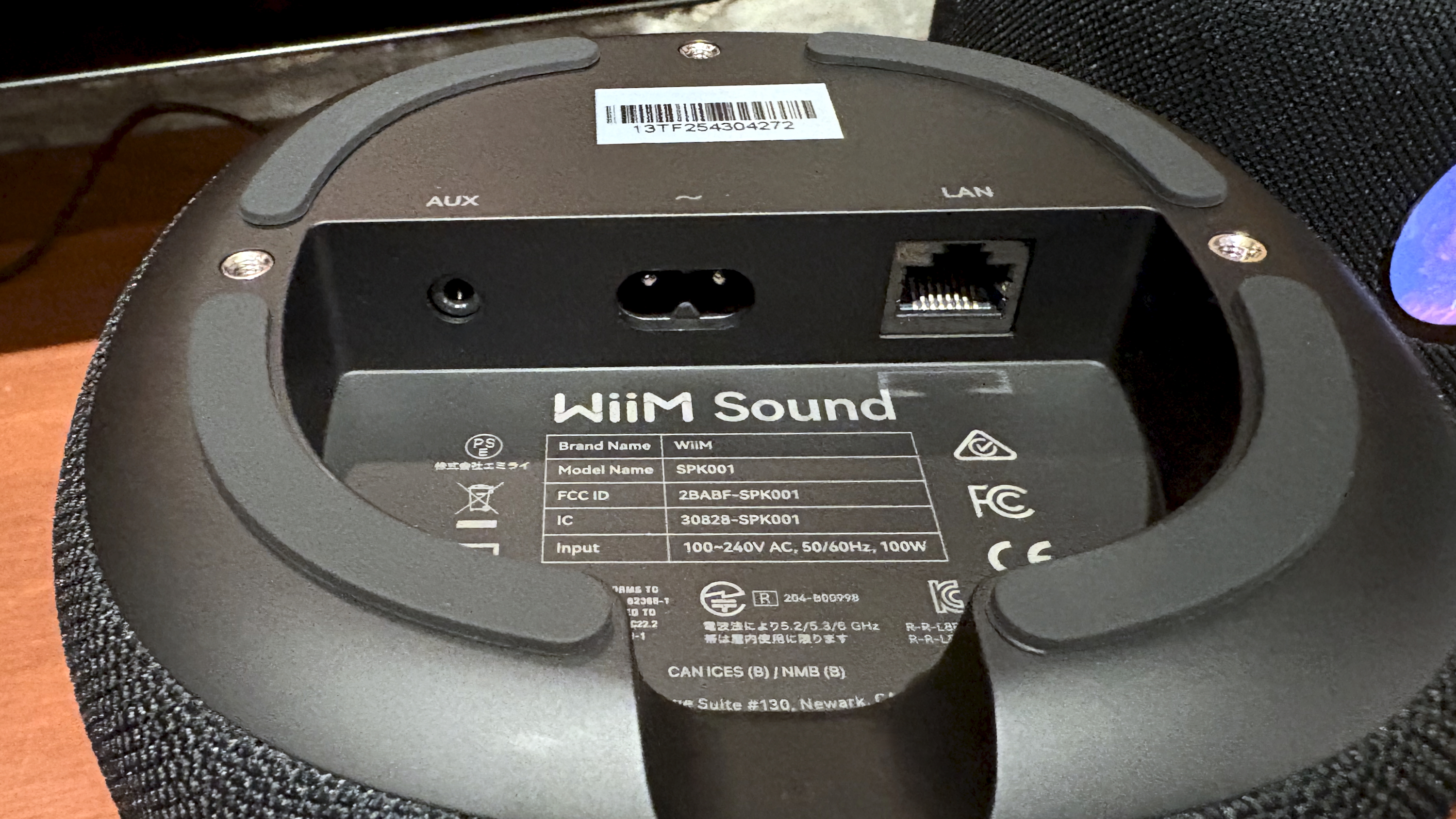 The WiiM Sound, in a home, on a varnished wooden table, showing the illuminated front panel