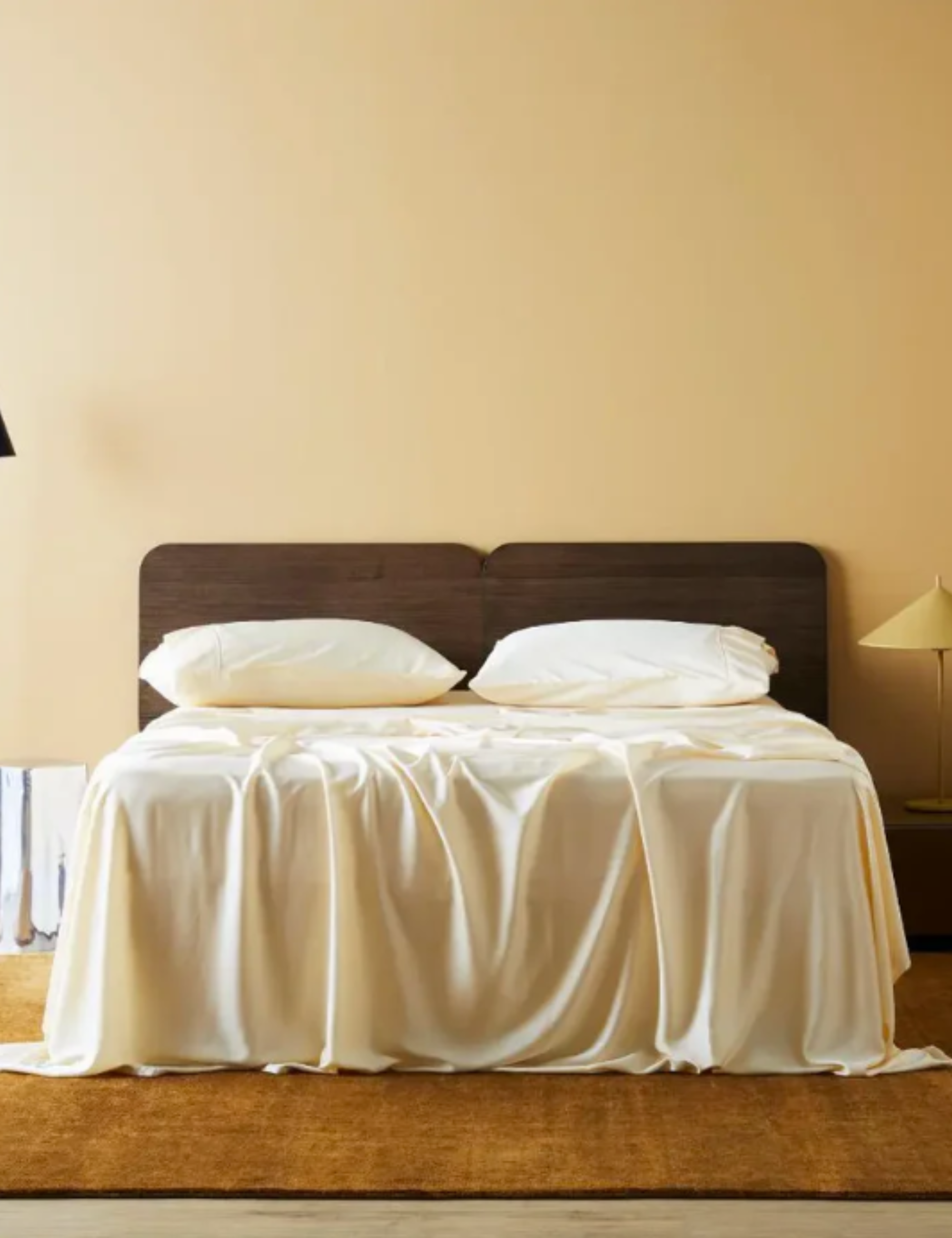 Cream bed sheets styled in a warm minimalist bedroom
