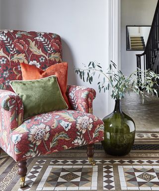 Patterned fabric chair in a room with a tiled floor and plant