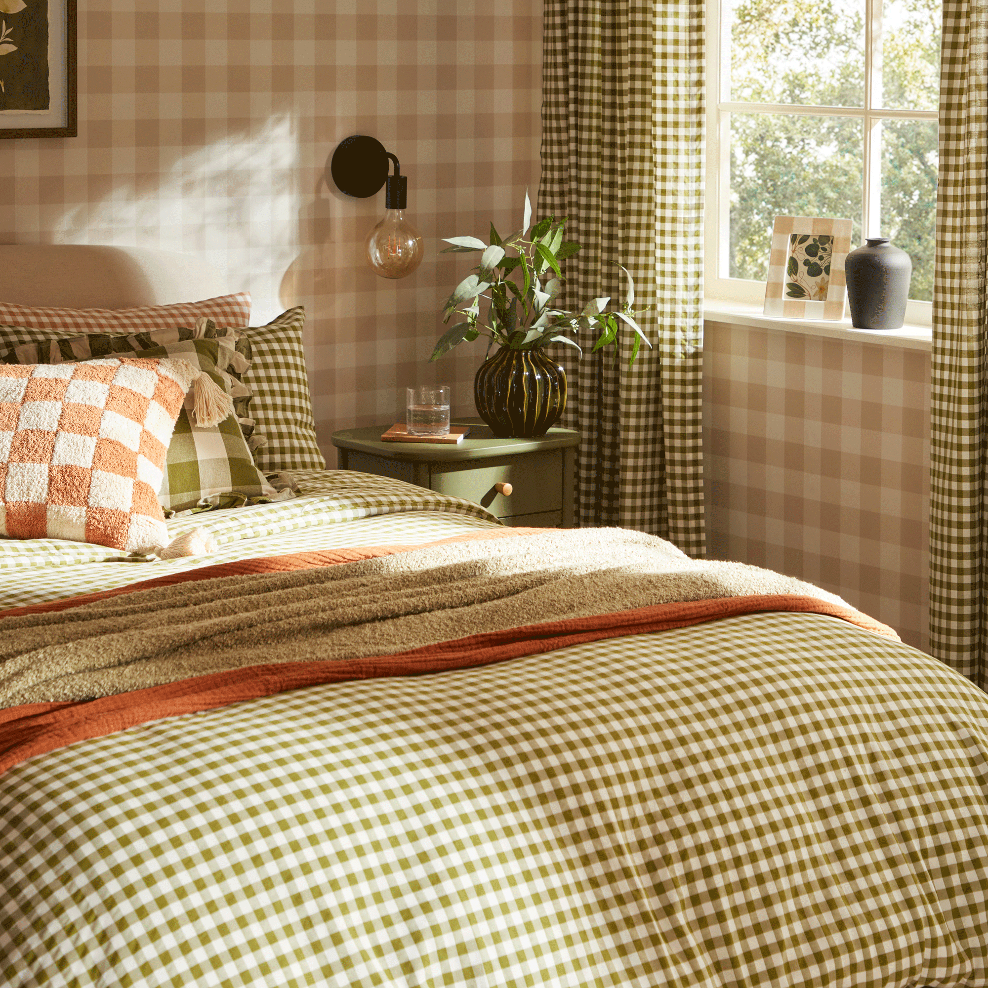 a bedroom with gingham wallpaper, gingham curtains and gingham bedding in various shades of cream, beige, green and orange
