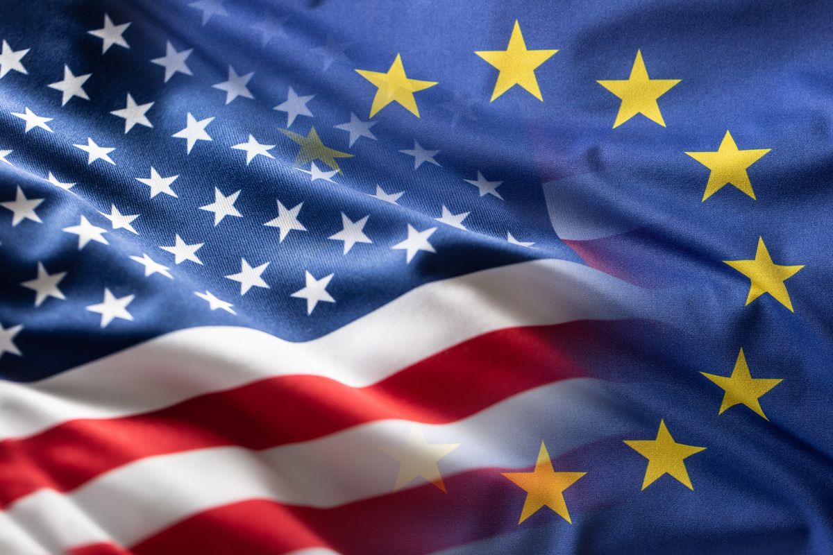 A cross fade between the US flag in the bottom left half of the frame, and the EU flag in the top right of the frame.