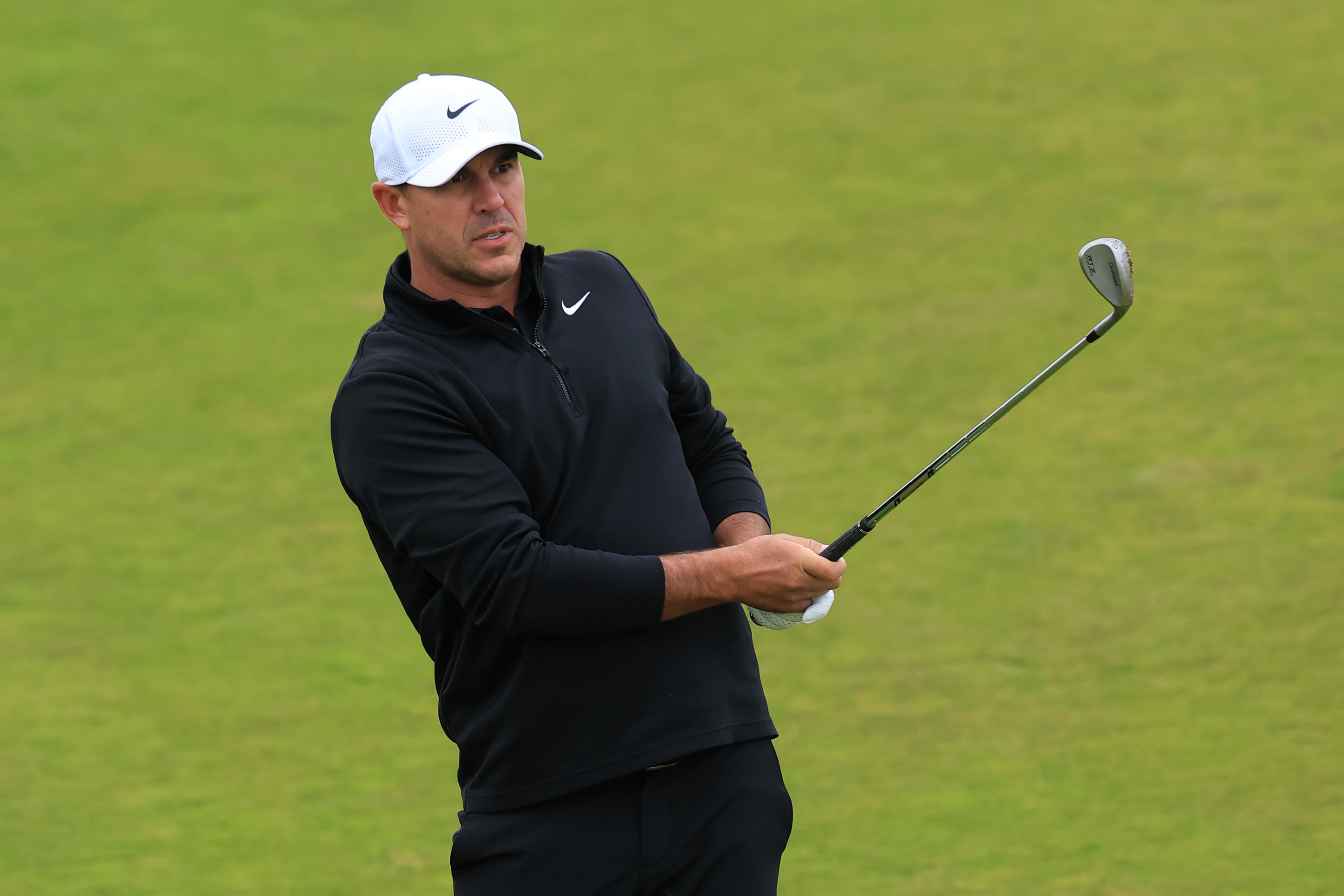 Brooks Koepka hits a wedge shot and watches it