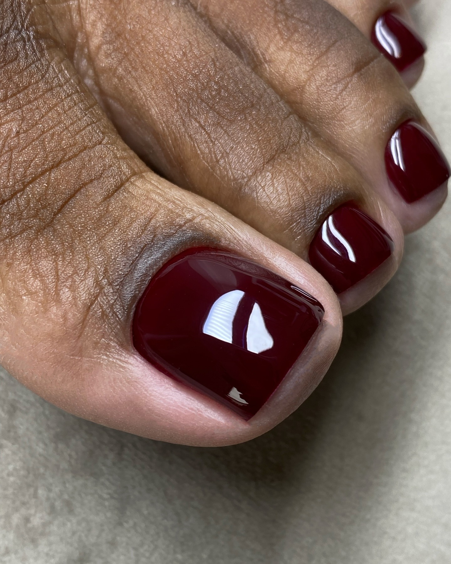 Un primo piano di una pedicure color bordeaux lucido