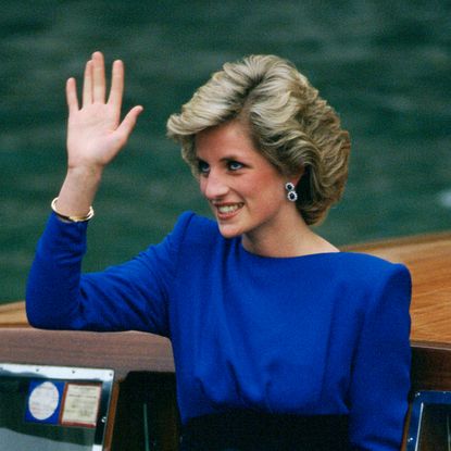 Princess Diana waving in a blue dress on a boat
