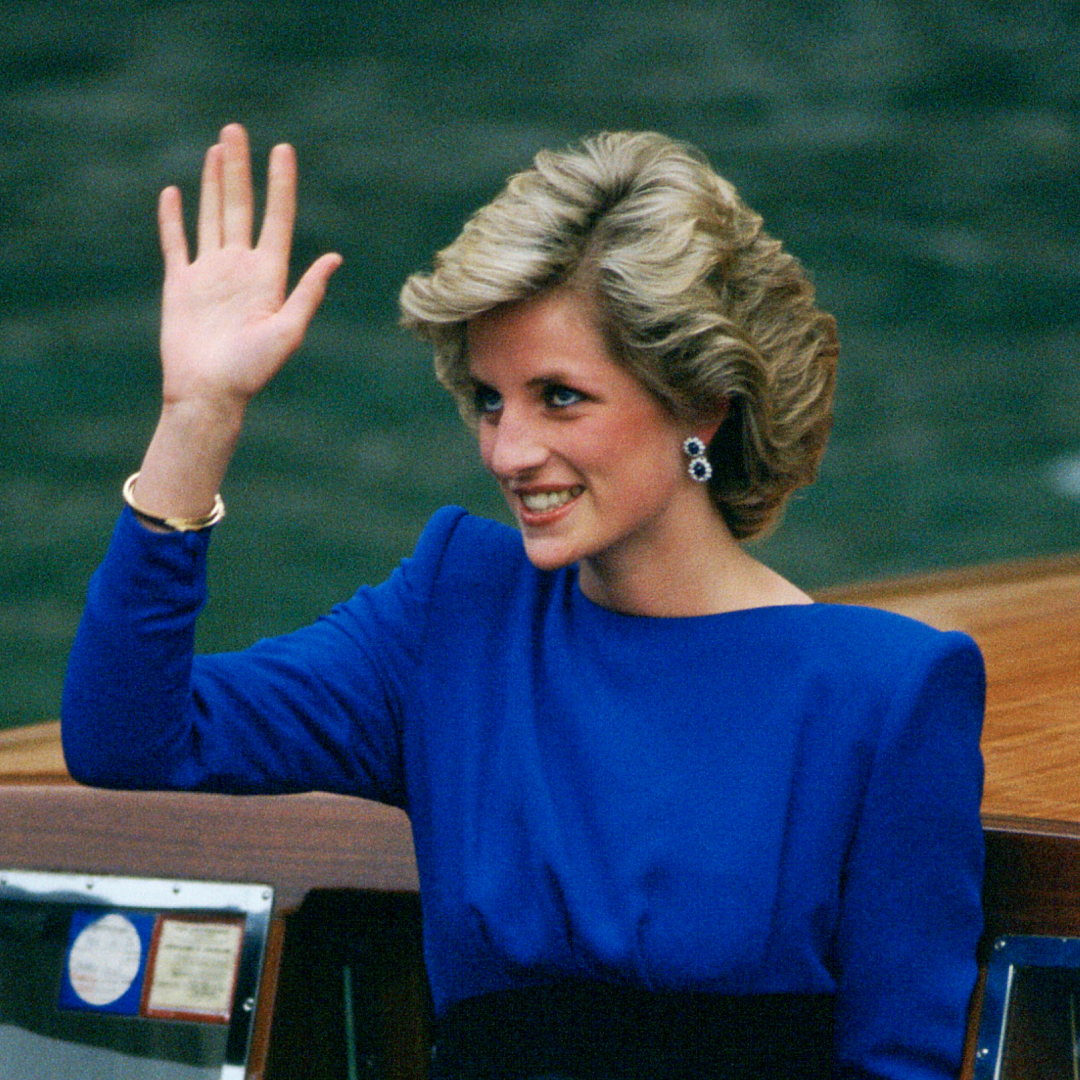 Princess Diana waving in a blue dress on a boat