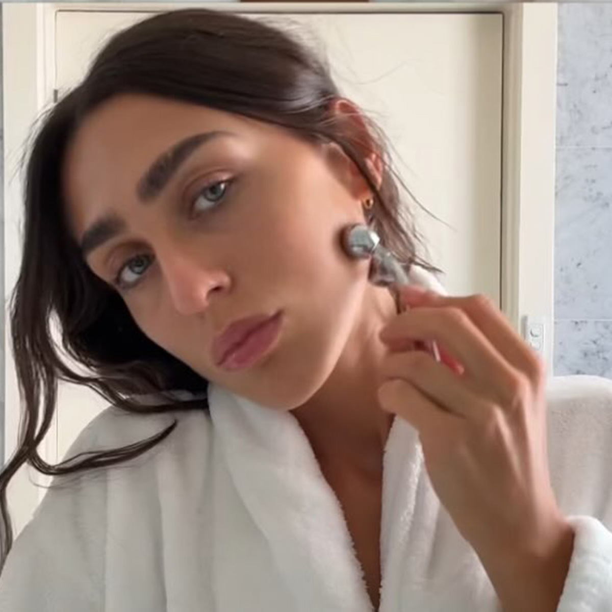 Camelia Farhoodi using a face massage beauty tool. 