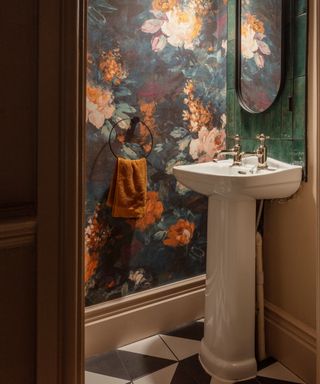 traditional white floor standing basin in bathroom with floral wallpaper, green tiled splash back and black and white tiled floor