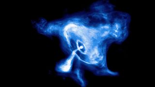 A blue and white glowing view of the Crab Nebula. It looks like there's a ring of gassy material around a dot that's giving off a stream of gas itself.