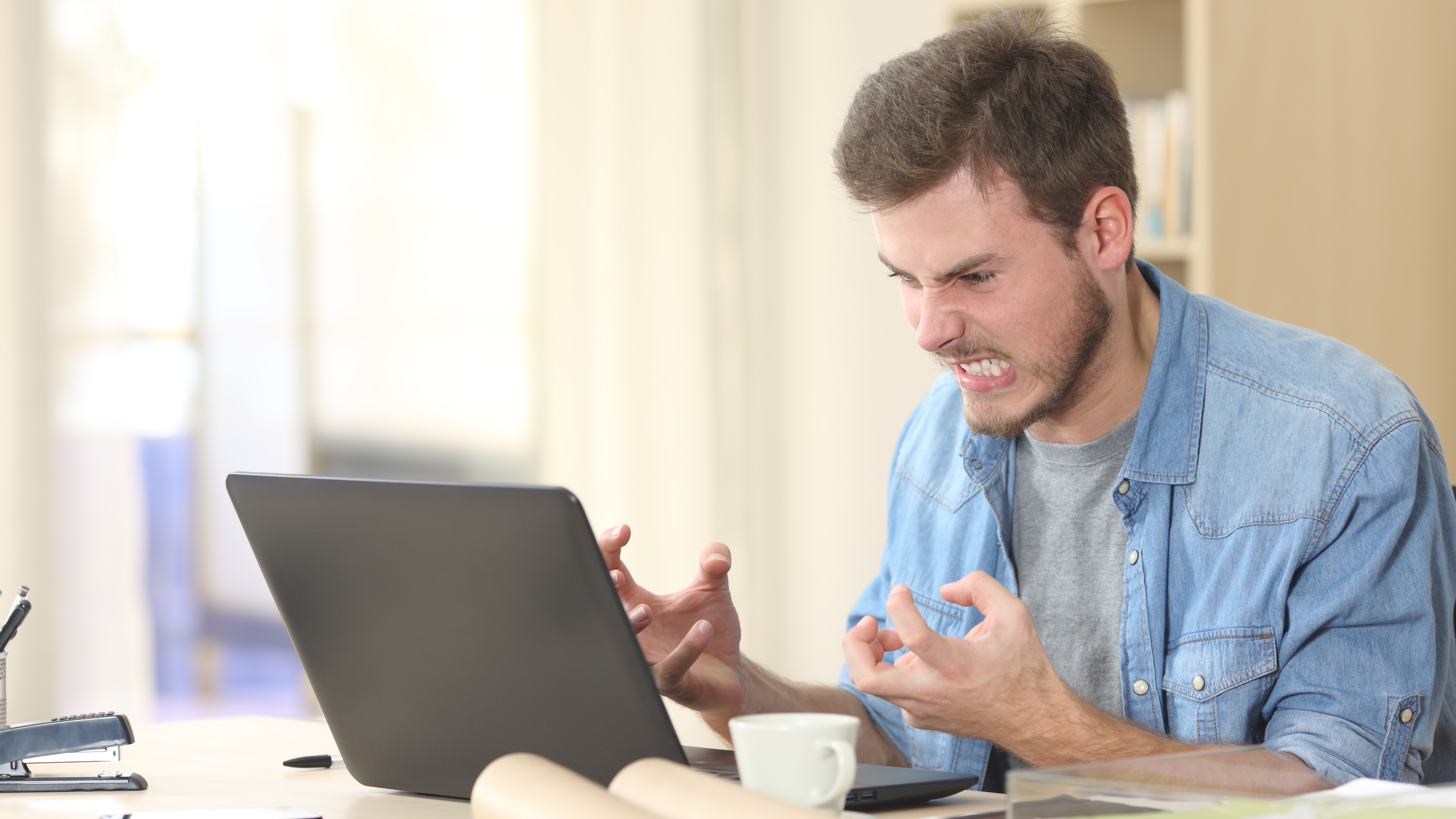 Hombre enojado con su computadora portátil.