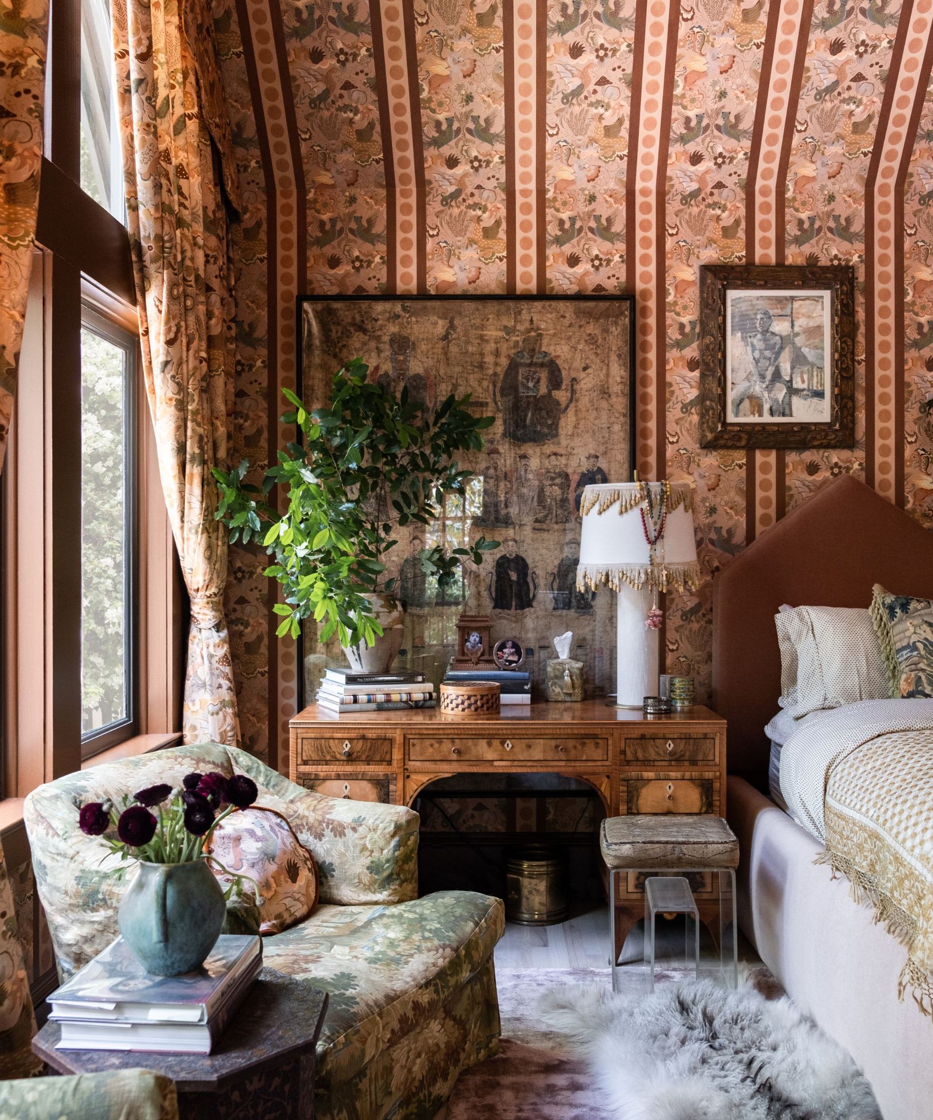 Eclectic bedroom with printed wallpaper, floral armchair, fluffy rug and wooden antique vanity table