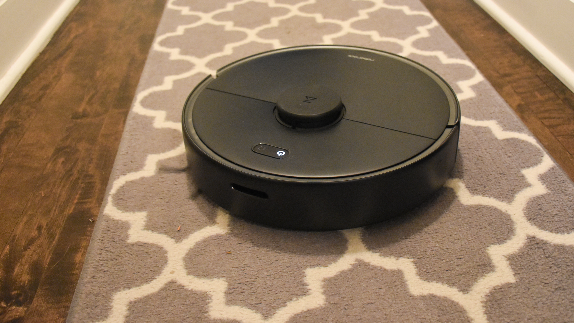 A Roborock S4 Max robot vacuum cleaning patterned floor runner on top of hardwood floor