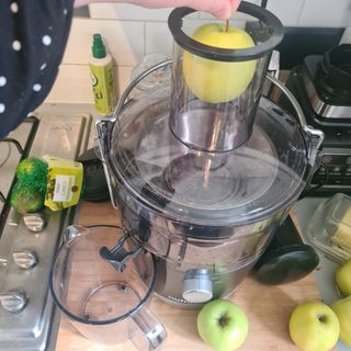Person using a nutribullet julicer with apples and limes