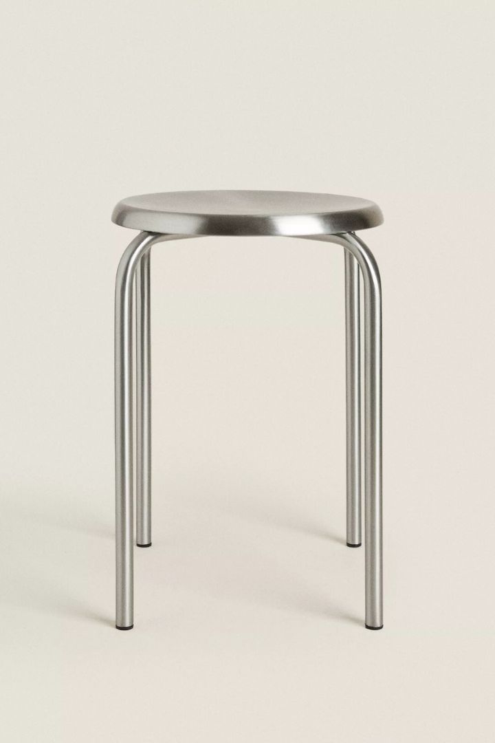 Stainless Steel Stool against plane beige background.