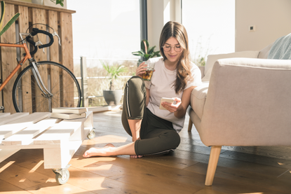 Woman drinking and looking at her phone, researching health benefits of alcohol