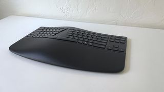 The HP 960 Ergonomic Keyboard on a white desk seen from the side